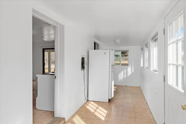a view of a hallway with windows and refrigerator