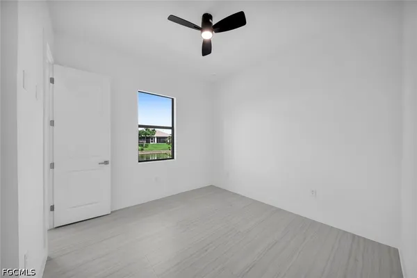 an empty room with a window and a ceiling fan