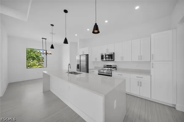 a kitchen with stainless steel appliances a stove a sink a refrigerator a center island and a window