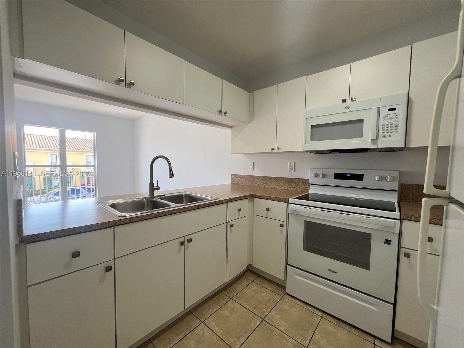 9720 Southwest 184th Street, Unit 210 Cutler Bay, FL 33157 - Photo 3 of 12 a kitchen with granite countertop white cabinets white stainless steel appliances and sink