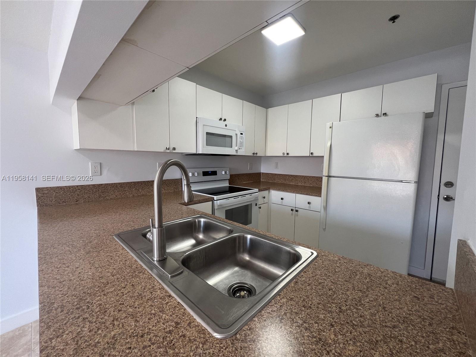 9720 Southwest 184th Street, Unit 210 Cutler Bay, FL 33157 - Photo 6 of 12 a kitchen with a sink a refrigerator and cabinets
