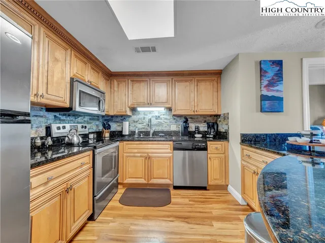 a kitchen with granite countertop a stove top oven a sink dishwasher and cabinets with wooden floor