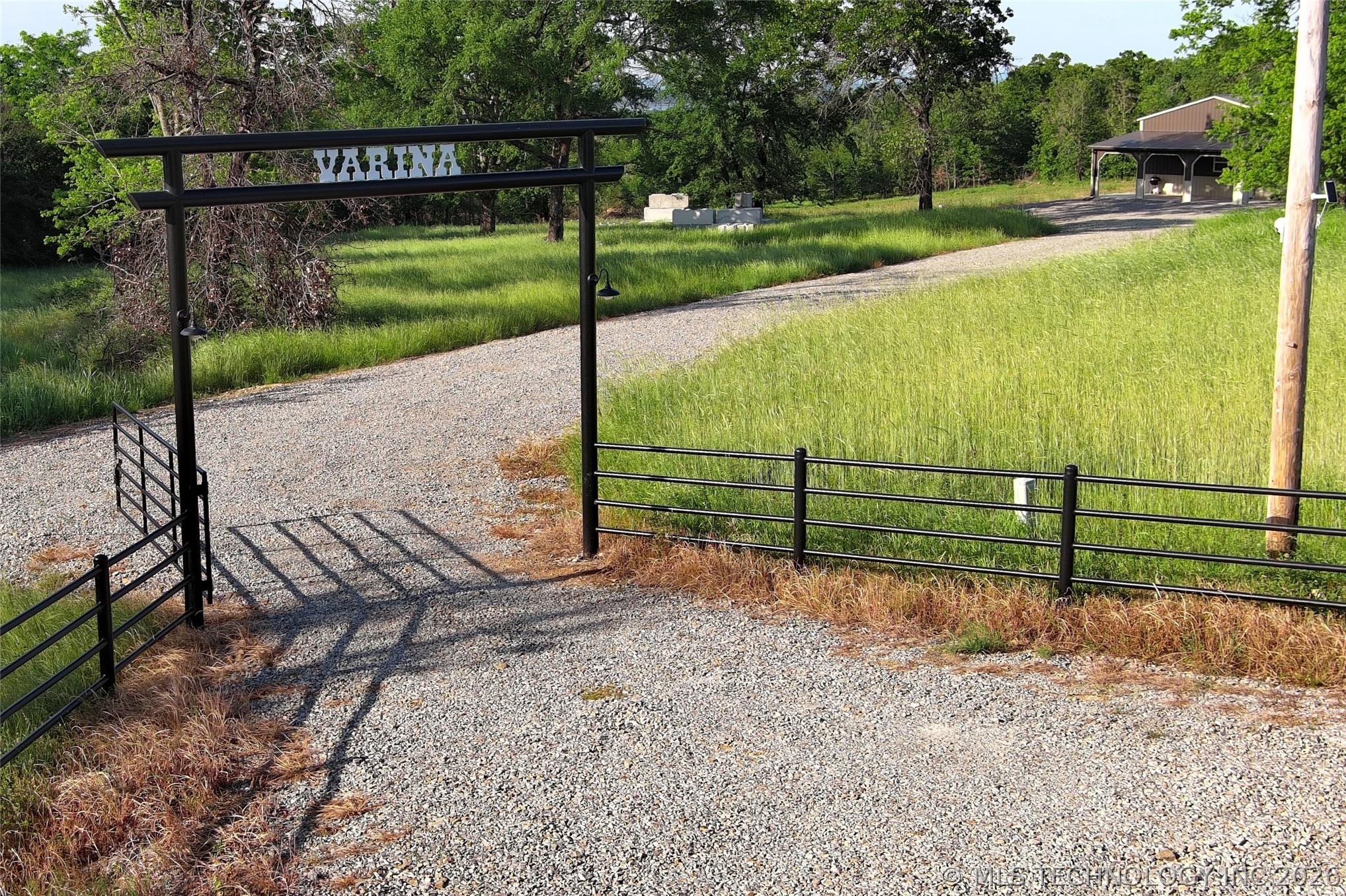 20862 East 1160th Road Keota, OK 74941 - Photo 2 of 47 Gravel driveway entrance featuring a black metal gate and archway with property name