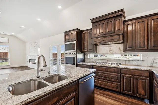 a kitchen with stainless steel appliances granite countertop a sink a stove and cabinets
