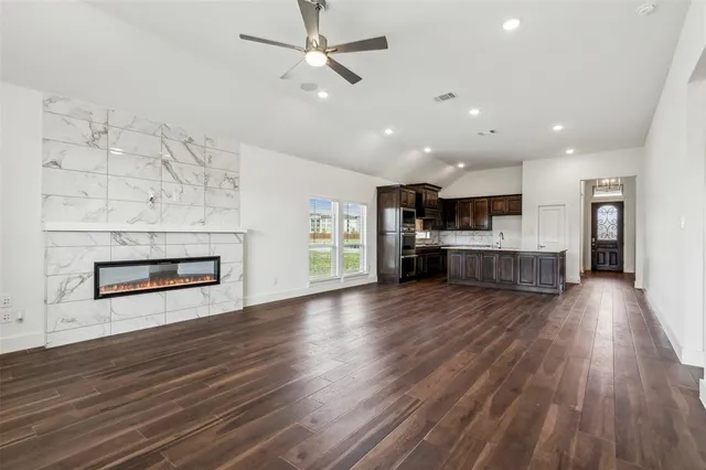 an empty room with wooden floor kitchen view and a kitchen
