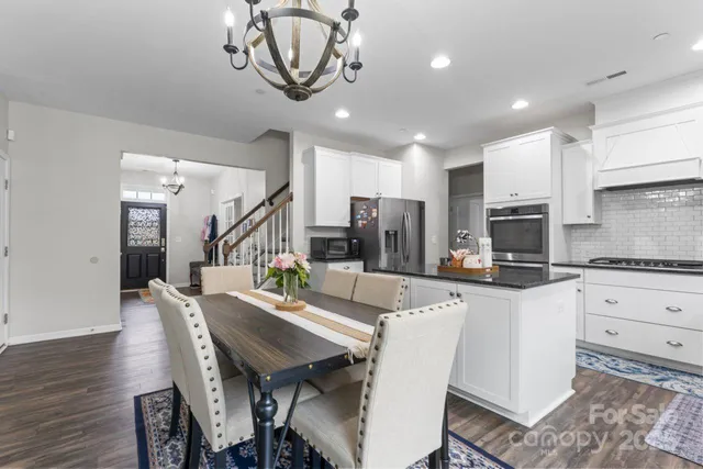 a view of kitchen with stainless steel appliances granite countertop a stove a sink dishwasher a dining table and chairs with wooden floor
