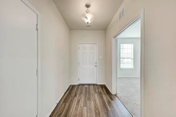 a view of a hallway with wooden floor and a bathroom