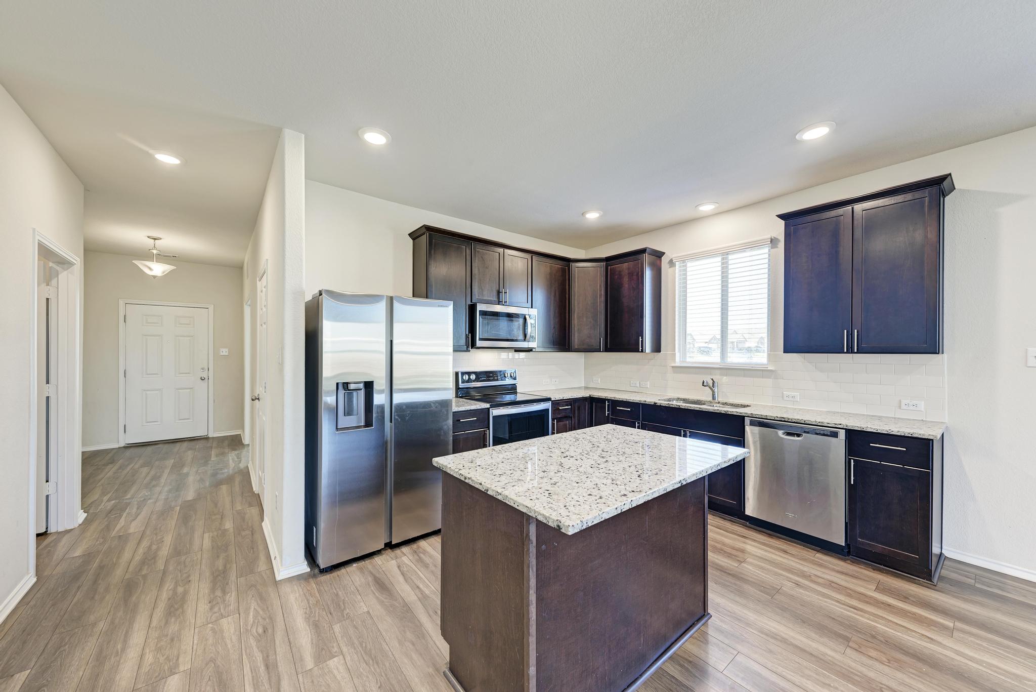201 Pivot Drive Taylor, TX 76574 - Photo 6 of 34 a kitchen with a center island wooden floor stainless steel appliances and cabinets