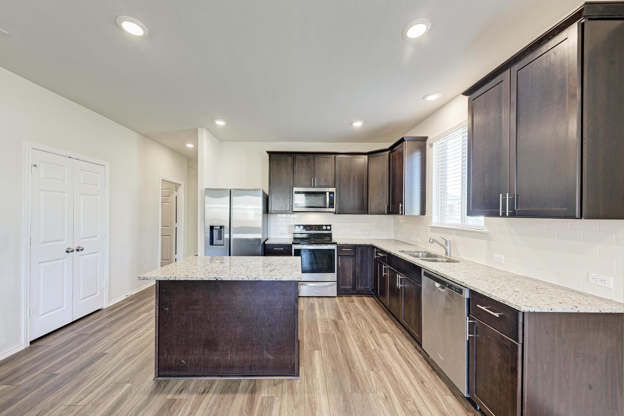 201 Pivot Drive Taylor, TX 76574 - Photo 7 of 34 a large kitchen with stainless steel appliances kitchen island granite countertop a large counter top and wooden floors