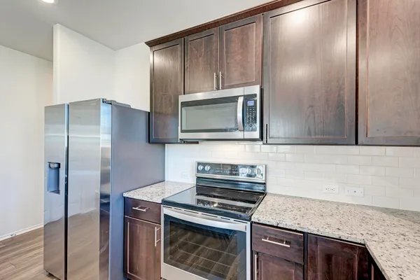 a kitchen with stainless steel appliances granite countertop a stove a microwave and a refrigerator