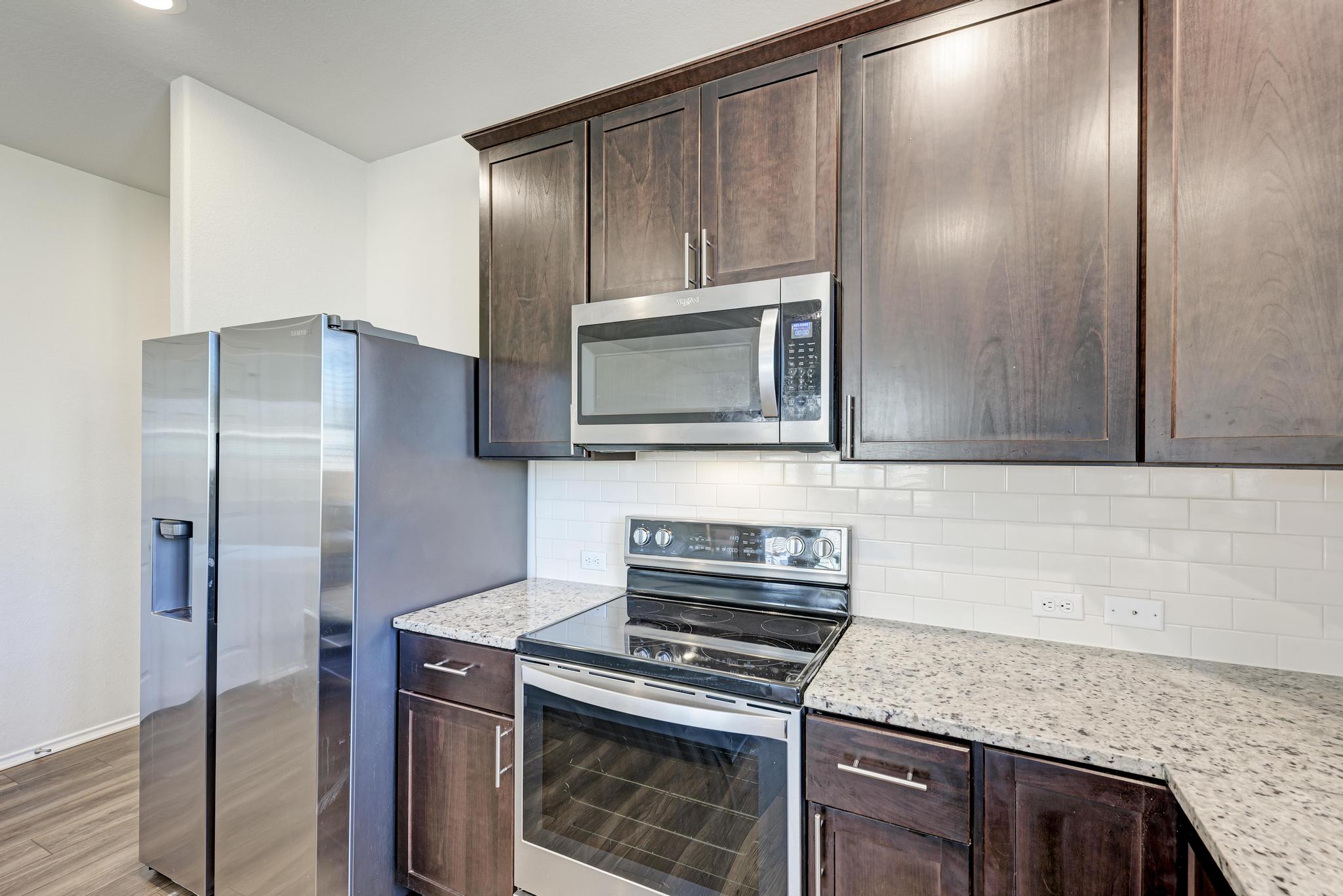 201 Pivot Drive Taylor, TX 76574 - Photo 10 of 34 a kitchen with stainless steel appliances granite countertop a stove a microwave and a refrigerator