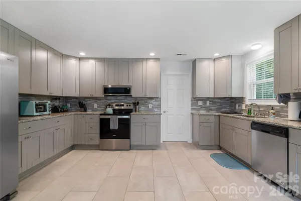 a kitchen with granite countertop a stove top oven sink and cabinets