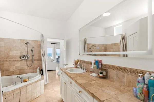 a bathroom with a granite countertop sink a mirror a bathtub and shower