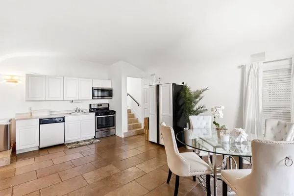 a kitchen with stainless steel appliances kitchen island granite countertop a table chairs and a refrigerator
