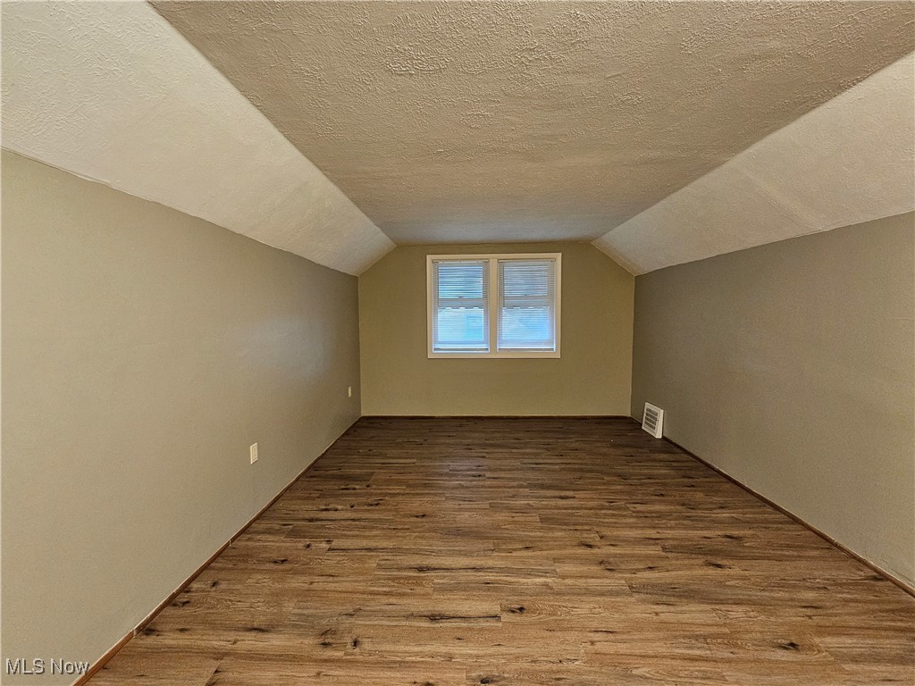 13514 Granger Road Cleveland, OH 44125 - Photo 14 of 23 Bonus room featuring light hardwood / wood-style flooring, vaulted ceiling, and a textured ceiling