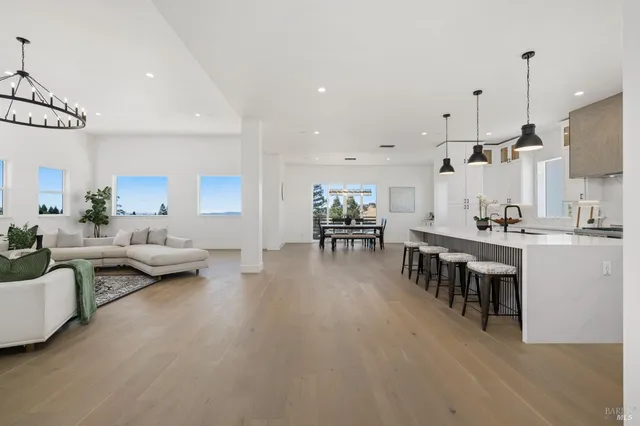 a kitchen with stainless steel appliances granite countertop a sink a stove a refrigerator and island with wooden floor