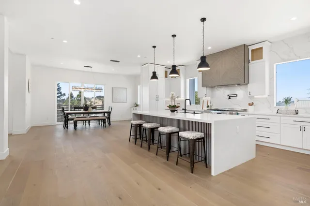 a kitchen with stainless steel appliances granite countertop a sink a stove a refrigerator and island with wooden floor