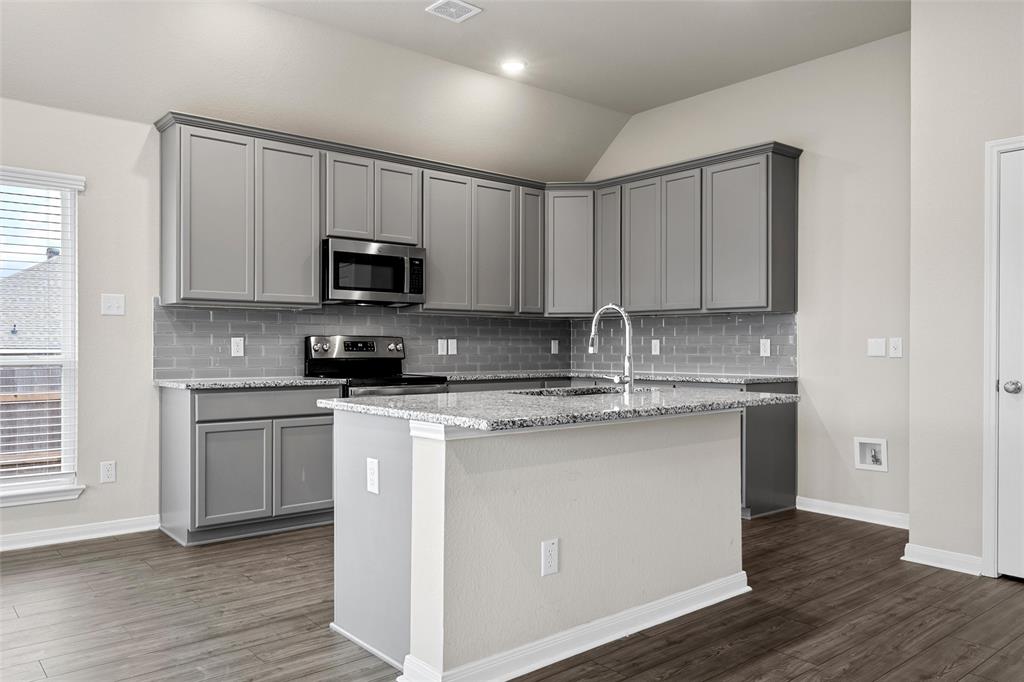 3208 Dottavio Road Lorena, TX 76655 - Photo 12 of 31 Kitchen featuring a central island, light gray cabinetry, stainless steel appliances, a subway tile backsplash, and wood-finish flooring