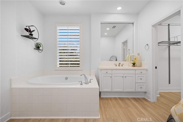 a spacious bathroom with a tub sink and mirror