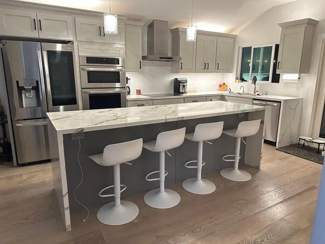 a kitchen with stainless steel appliances granite countertop a sink a stove a refrigerator cabinets and chairs