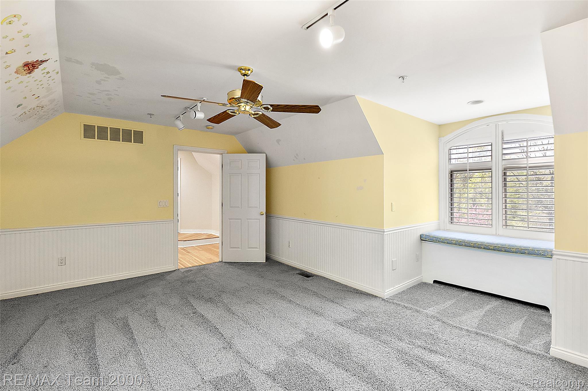 630 Sheldon Court Rochester, MI 48306 - Photo 65 of 94 Empty room featuring rail lighting, light carpet, ceiling fan, a wainscoted wall, and vaulted ceiling