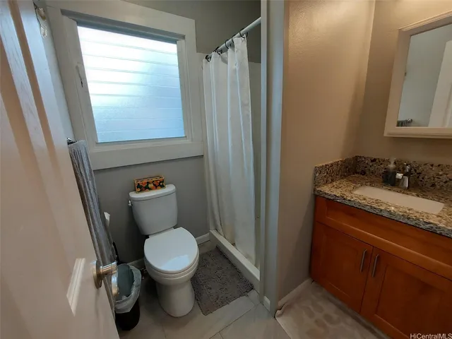 a bathroom with a granite countertop toilet a sink and a mirror