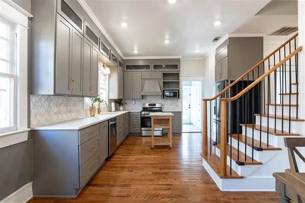 a large kitchen with stainless steel appliances wooden floor and a large window
