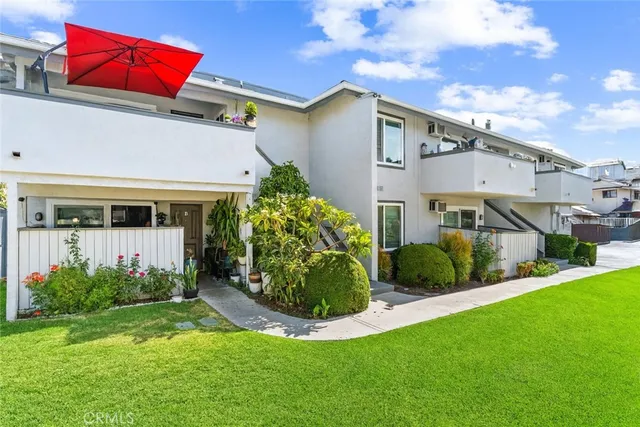 a view of a white house next to a yard with potted plants