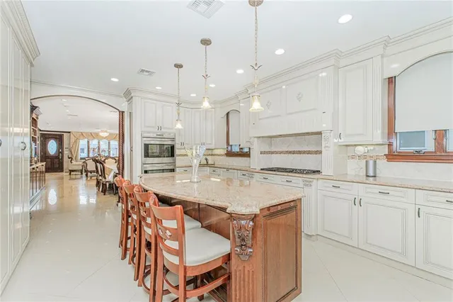 a large kitchen with cabinets chairs and wooden floor