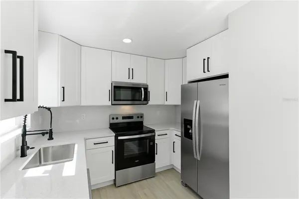 a kitchen with stainless steel appliances a refrigerator sink and white cabinets