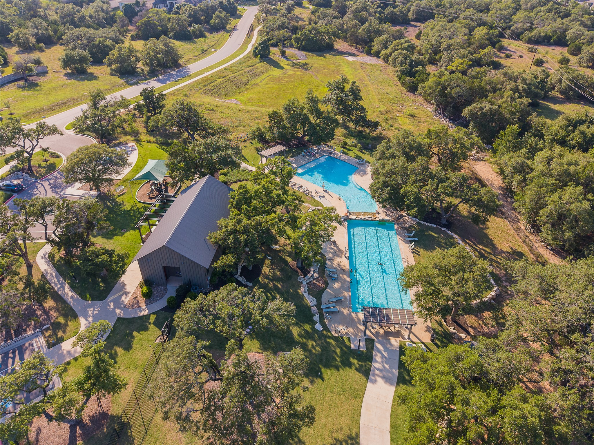 320 Old Stone Road Austin, TX 78737 - Photo 38 of 40 An aerial perspective reveals a charming community clubhouse, two inviting pools, and a lush, verdant landscape.