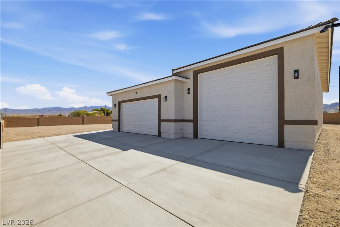 1061 Factory Road Pahrump, NV 89048 - Photo 3 of 41 A spacious concrete driveway leads to a modern two-door garage, offering ample parking and storage.