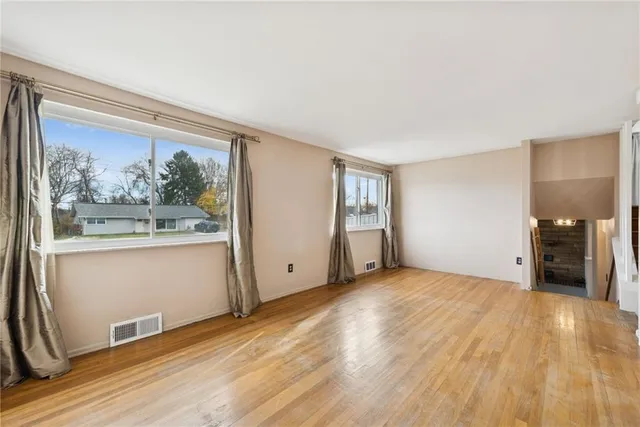 a view of a big room with wooden floor and windows