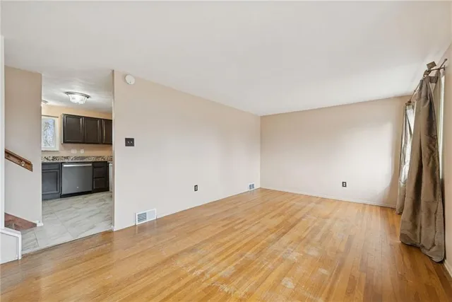 a view of empty room with wooden floor and electronic appliances