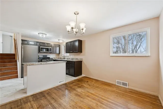 a kitchen with stainless steel appliances granite countertop a refrigerator oven a sink dishwasher and white cabinets with wooden floor