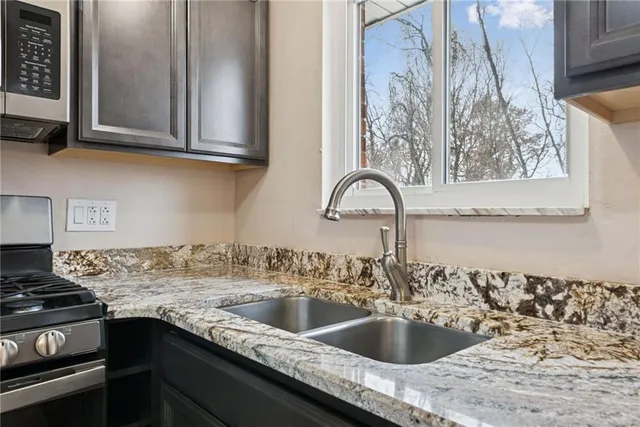 a kitchen with granite countertop a sink stainless steel appliances and cabinets