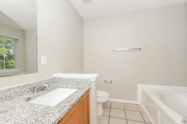 a bathroom with a granite countertop sink a toilet and bathtub