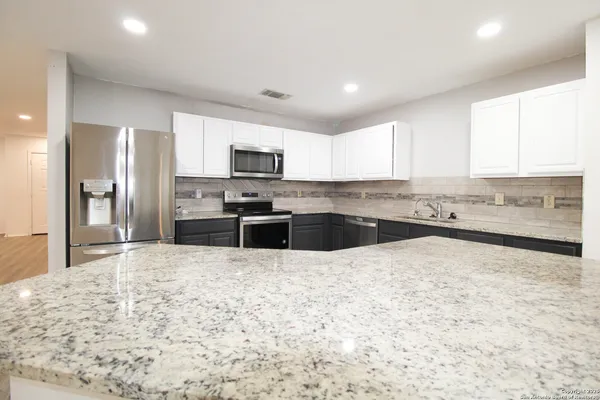 a large kitchen with granite countertop a stove a sink a microwave a counter space and cabinets