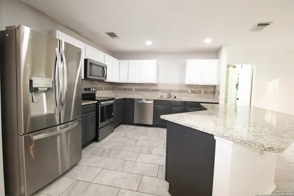 a kitchen with stainless steel appliances granite countertop a refrigerator a sink a stove and oven