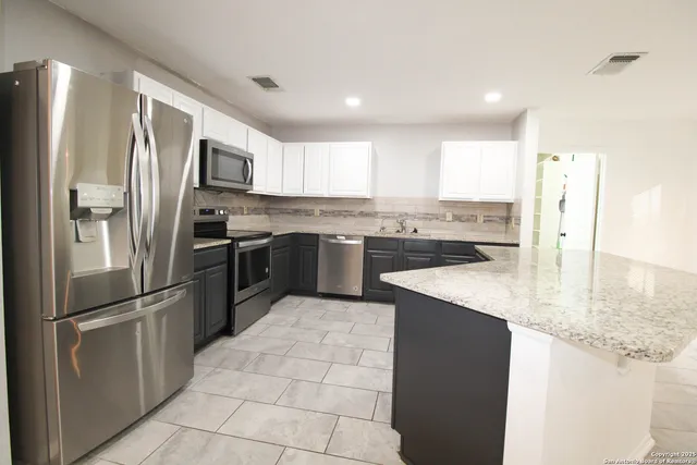 a kitchen with stainless steel appliances granite countertop a refrigerator a sink a stove and oven