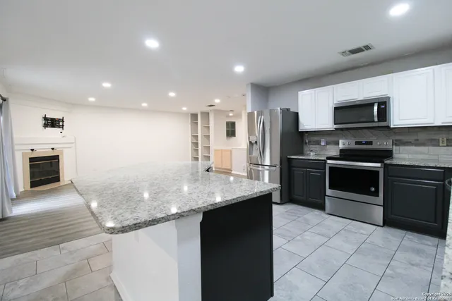 a kitchen with kitchen island granite countertop a stove sink and microwave