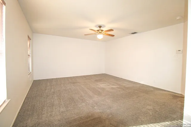 an empty room with a window and a ceiling fan