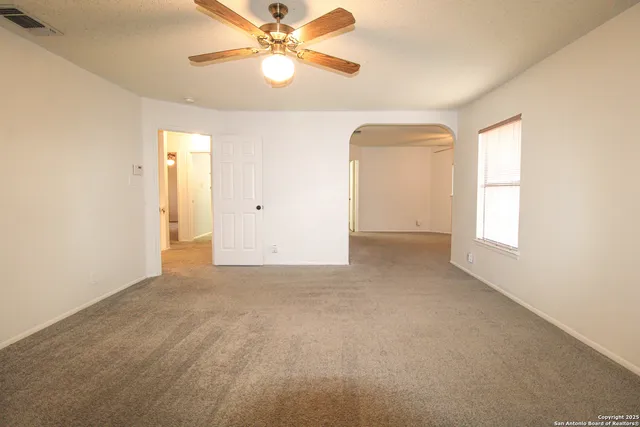 an empty room with a window and a fan