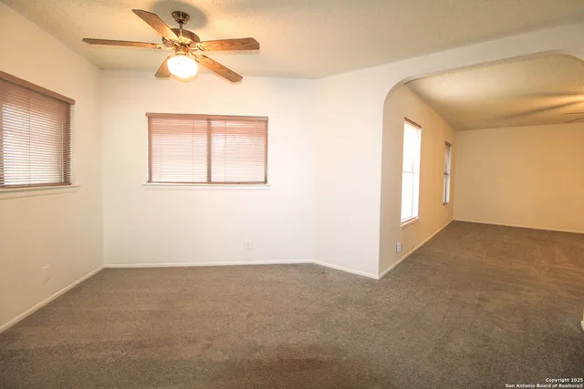 an empty room with windows and fan
