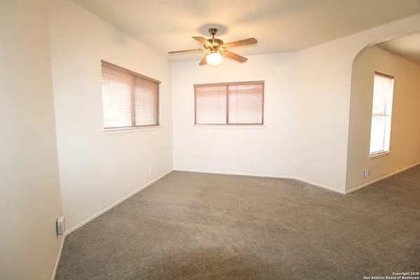 an empty room with a window and a fan