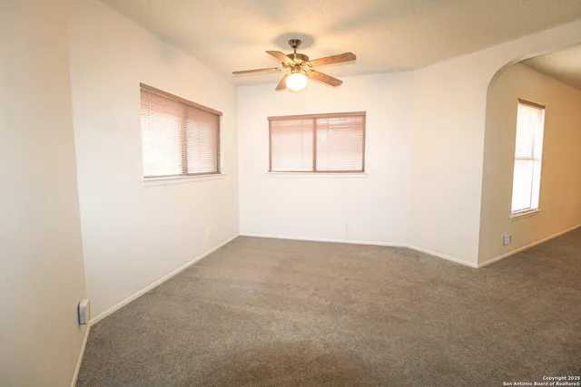 an empty room with a window and a fan