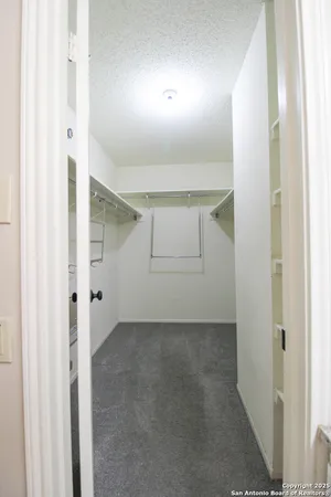 an empty room with windows and chandelier fan