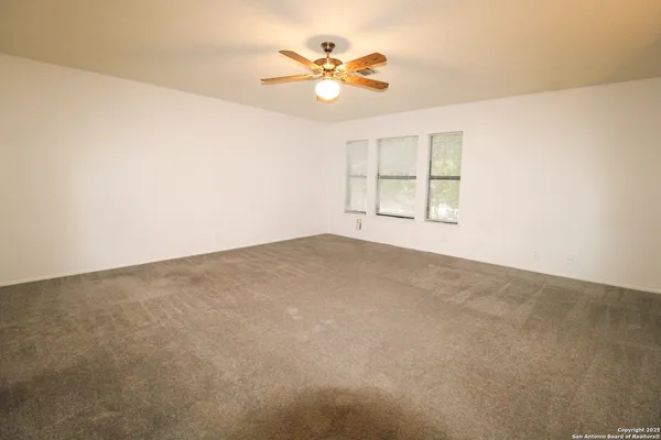 an empty room with windows and chandelier fan