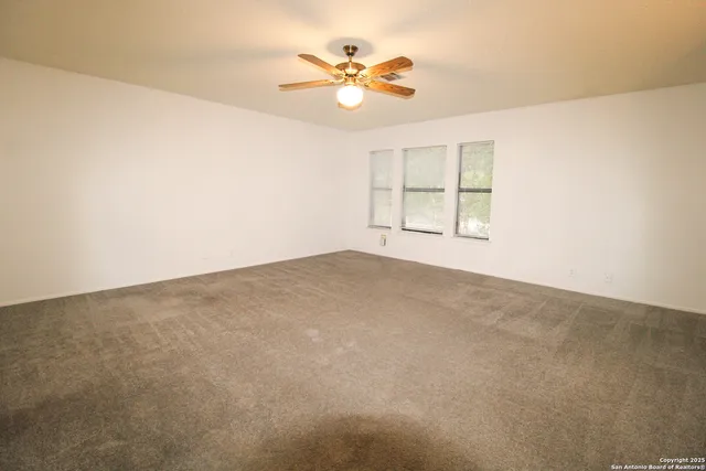 an empty room with windows and chandelier fan