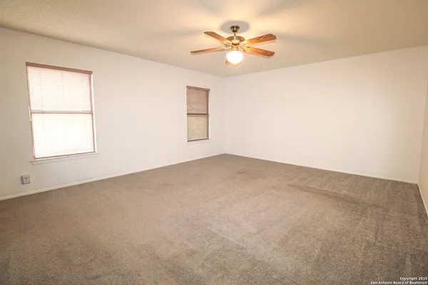 an empty room with windows and fan